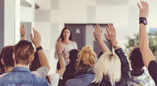 Woman discussing and people are raising their hands