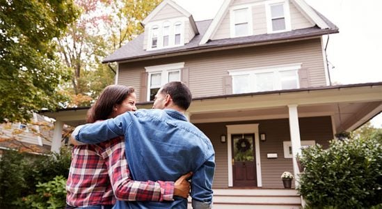 Young couple in front of their new home