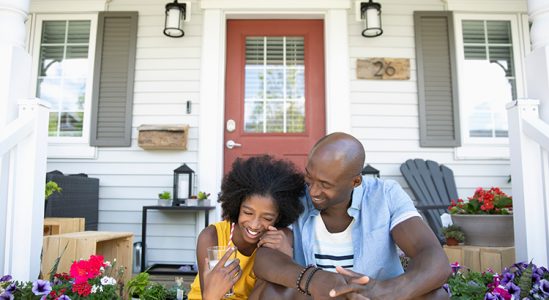 Couple sitting in front of their home