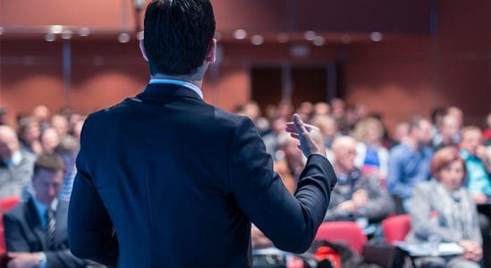 Man on his back doing a speech in front of people