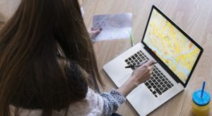 Woman using laptop and looking at her paper