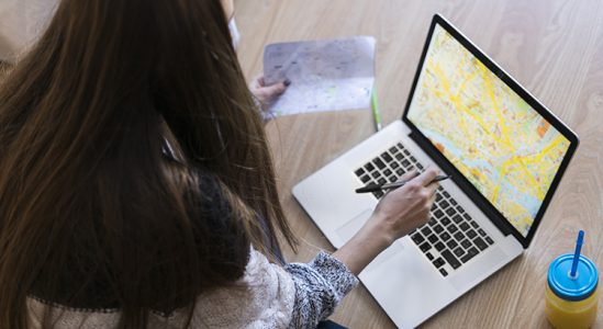 Woman using laptop and looking at her paper