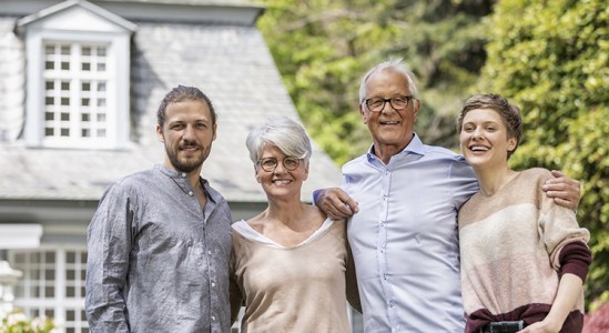 Senior couple with young man and woman in front of house