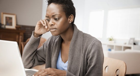 Woman looking stressed while using laptop