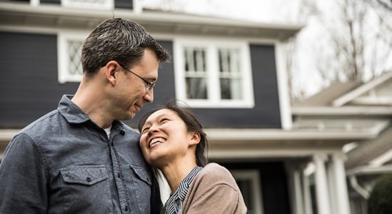 Happy couple staring at each other in front of a home
