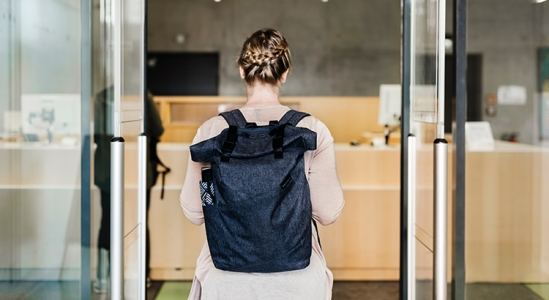 Woman wearing a backpack while entering a store