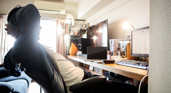 Man resting his back while looking at his laptop