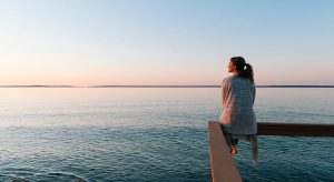 Young woman sitting on edge looks out at view