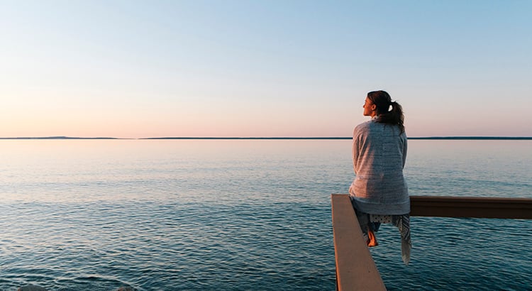 Young woman sitting on edge looks out at view