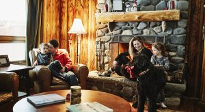 Family sitting by fireplace in winter cabin
