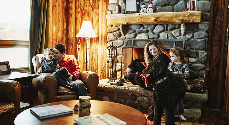 Family sitting by fireplace in winter cabin
