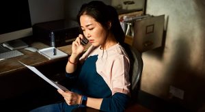 Korean woman on cell phone reading important document