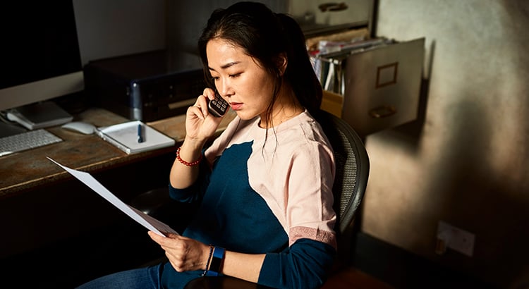 Korean woman on cell phone reading important document