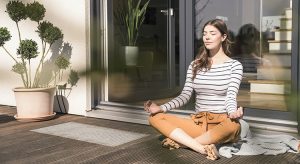 Young woman sitting on terrace at home practicing yoga