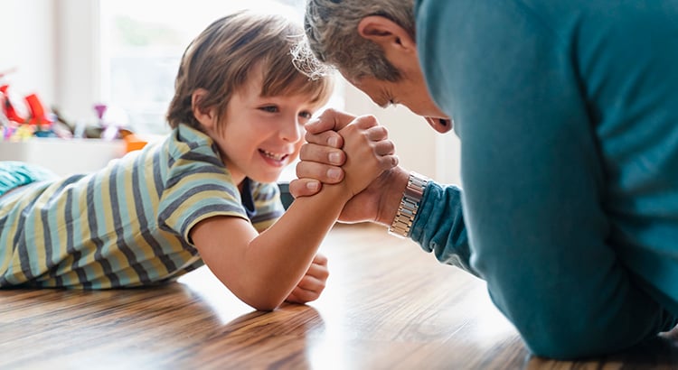 Father and son lying on the floor at home arm wrestling