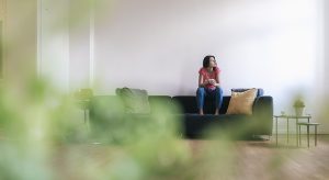 Woman at home sitting on sofa with cup of coffee
