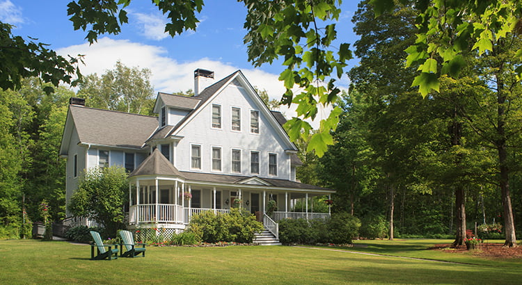 Victorian home with lawn and large front porch in summer