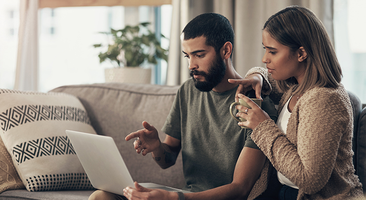 Young couple using a laptop on the sofa at home