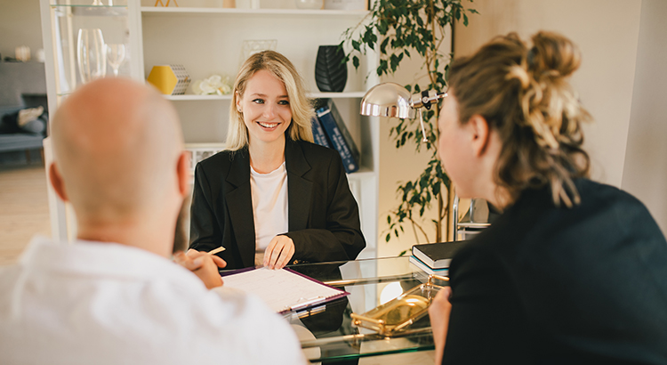 Happy couple having conversation with real estate agent in the office.