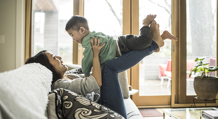 Mother playing with young son (2 yrs) on couch at home