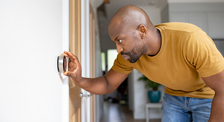 Man adjusting the temperature on the thermostat of his house